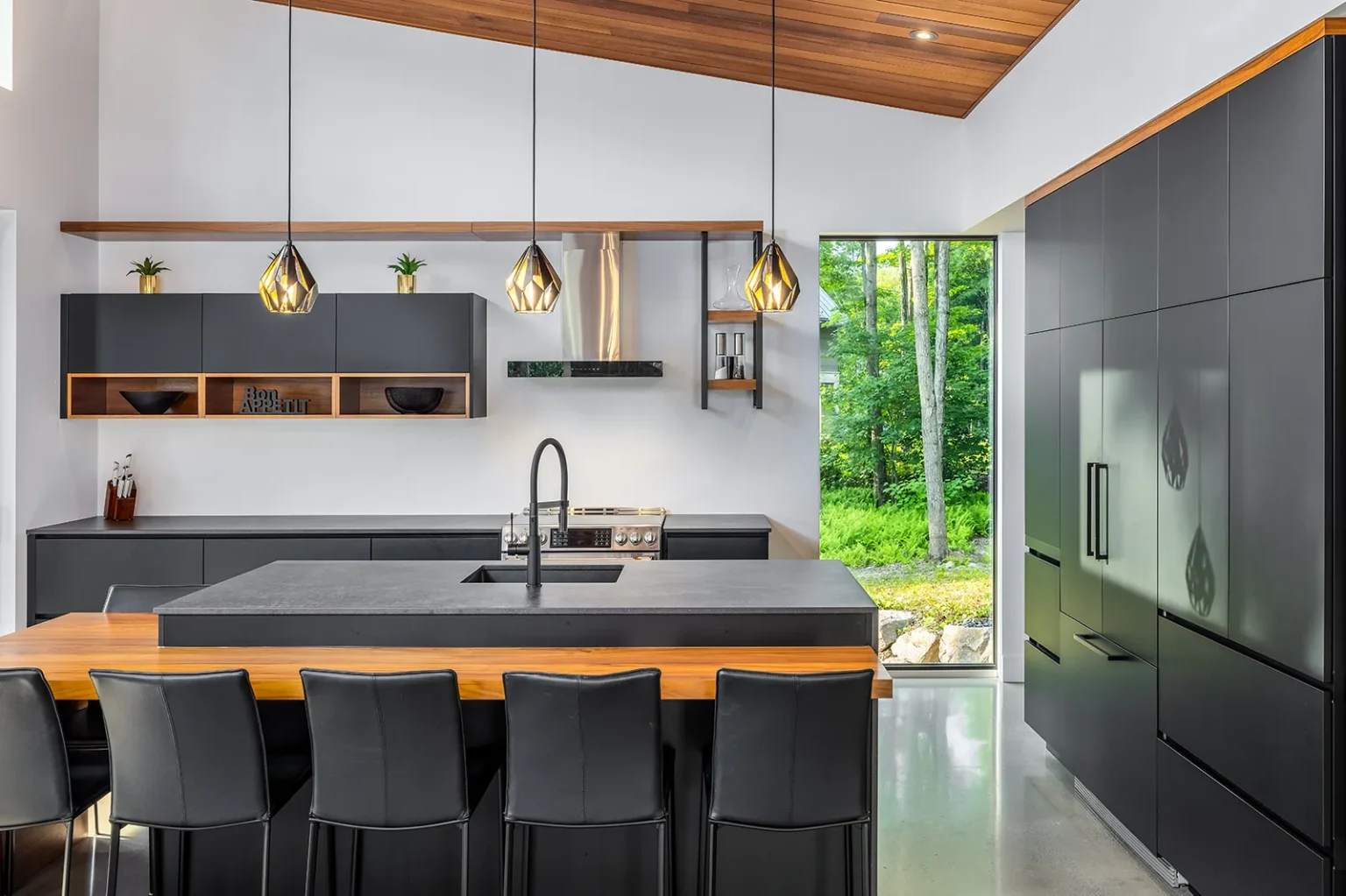 Cuisine au design audacieux avec armoires noires et plafond en bois à Bromont